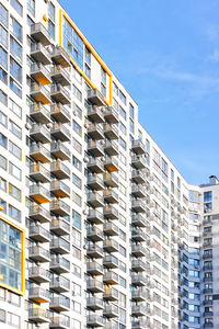 Rhythmic rows of balconies of a multi-storey residential building against the blue sky.