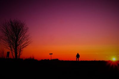 Silhouette man standing on land during sunset