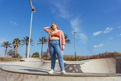 Young woman standing against sky