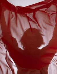 Young man with red transparent fabric in motion against white background. studio photography.