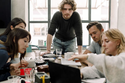 Businesswoman explaining while coworkers listening at workplace