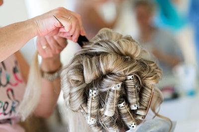 Cropped image of hairdresser styling customer hair in salon