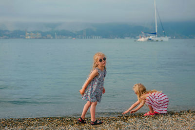 Women standing on shore by sea