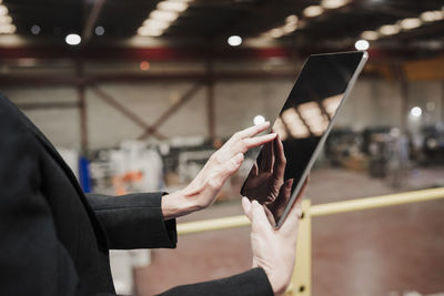 Hands of mature businesswoman using tablet computer at industry