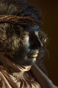 A woman with black painted face and golden clothes, party time, festival, close up portrait