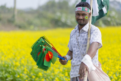 Portrait of smiling man holding yellow while standing outdoors