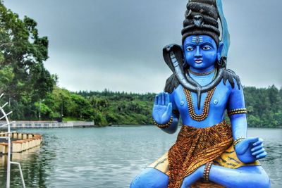 Shiva statue by sea against sky