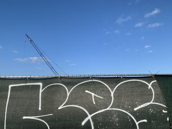 Low angle view of text on billboard against blue sky