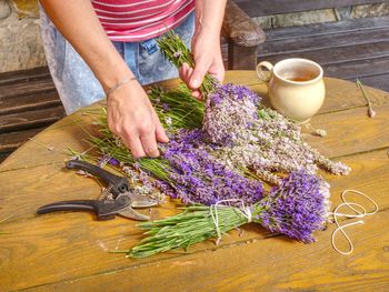 Hands of gardener woman create relaxing smell bouquet. herbal tea, stalks of lavender and scissors