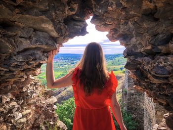 Woman in red dress surrounded by the old ruins of a fortress