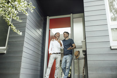 Father and son talking to each other while standing at door