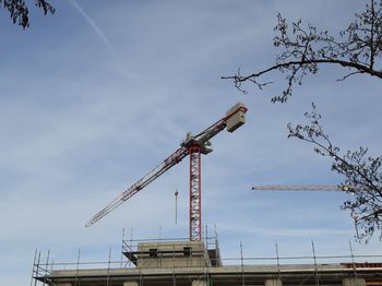 Low angle view of crane at construction site against sky