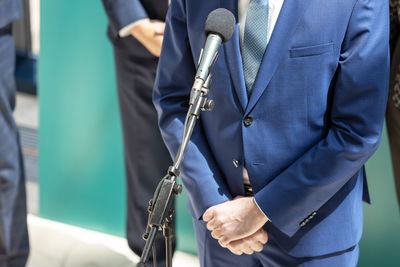 Midsection of people holding umbrella