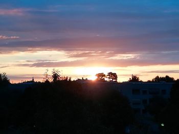 Silhouette trees and buildings against sky during sunset