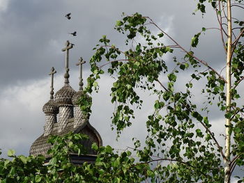 Low angle view of statue against trees and building against sky