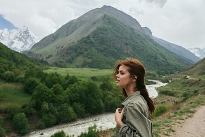 Portrait of young woman standing against mountain