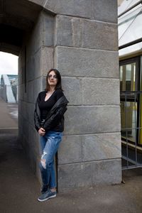 Portrait of young woman standing against wall