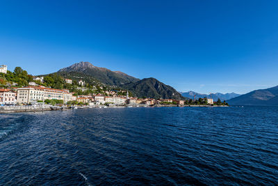 Scenic view of sea by buildings against clear blue sky