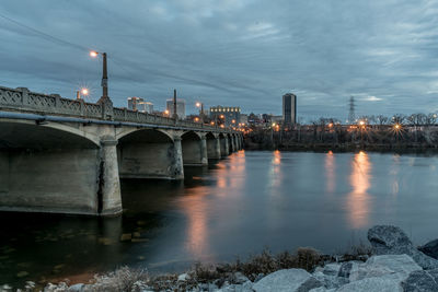 Illuminated bridge over river in city