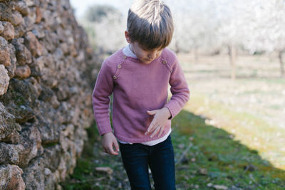 Boy standing against stone wall