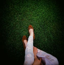 Low section of woman sitting on field at park