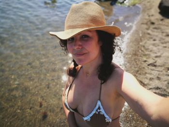 High angle view of woman wearing sun hat and bikini top standing at beach