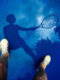 Reflection of woman playing tennis on wet court