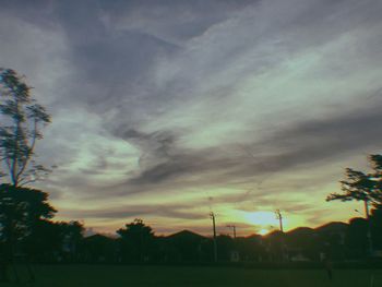 Low angle view of silhouette trees against dramatic sky