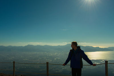 Young man standing on observation point against blue sky during sunset