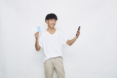 Man holding smart phone while standing against white background