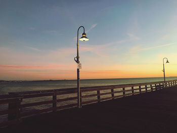 Street light on beach against sky during sunset