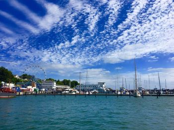 Sailboats moored in harbor against sky in city