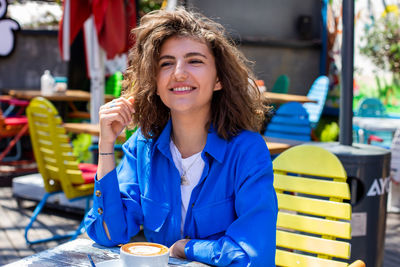 Portrait of young woman looking away while sitting at restaurant