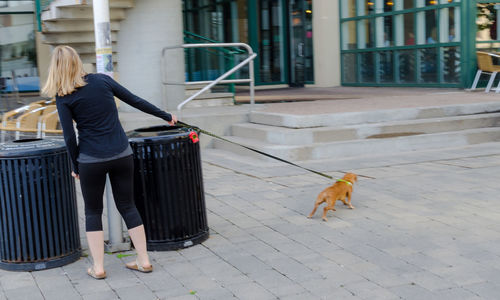 Man with dog walking in front of building