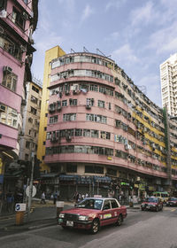 Cars on road by buildings against sky