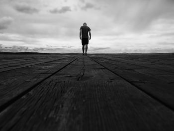 Rear view of man walking on jetty