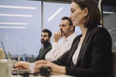 Dedicated businessman with male and female colleagues discussing in meeting at work place