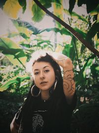 Portrait of young woman standing against plants