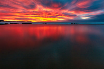 Scenic view of sea against dramatic sky during sunset