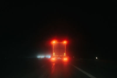 Illuminated road against sky at night