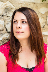 Close-up of thoughtful beautiful woman against wall