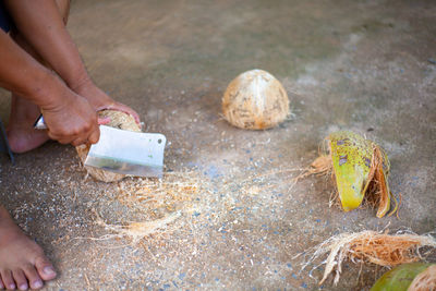 Low section of person cutting coconuts