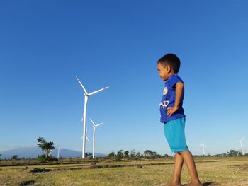 Full length of boy standing on field against clear sky