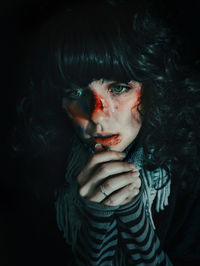 Close-up portrait of a serious young woman over black background