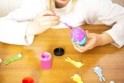 Child hands painting eggs for easter on the wooden table at home. preparation for easter celebration