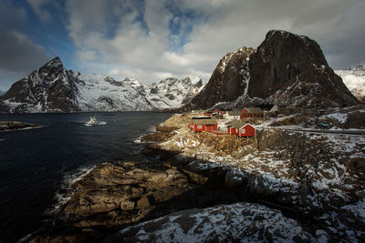 Scenic view of sea by snowcapped mountains against sky