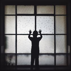 Silhouette man standing against window