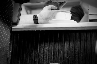 Cropped image of man holding spoon in coffee cup