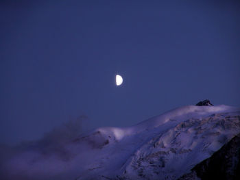 Scenic view of snow covered mountains against sky at night