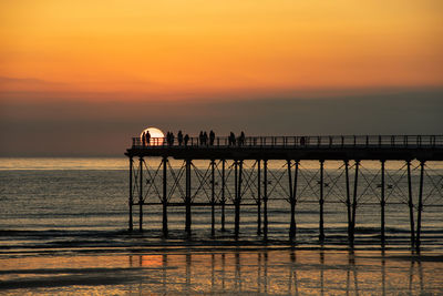 Silhouette pier over sea against sky during sunset